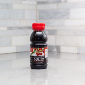 One 8 oz bottle of Montmorency tart cherry concentrate on a white counter with a white tiled backsplash