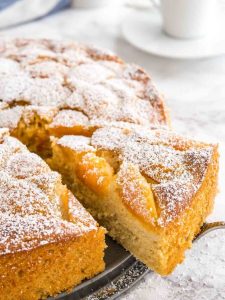 slice of apricot cake being served with powered sugar on top