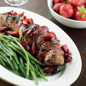 photo of pork tenderloin with strawberry sauce on a platter with green beans