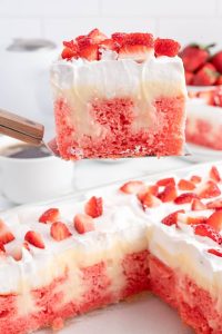 photo of slice of strawberry poke cake being served from the larger cake.